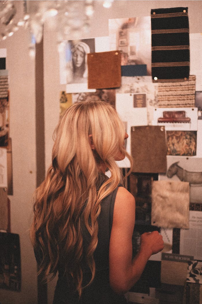 A woman admiring inspiration boards adorned with textures and art in a design studio.